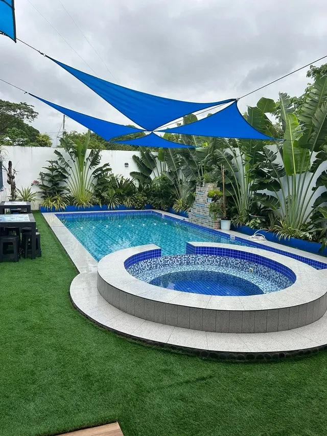 Pool and jacuzzi by day under blue shade sails