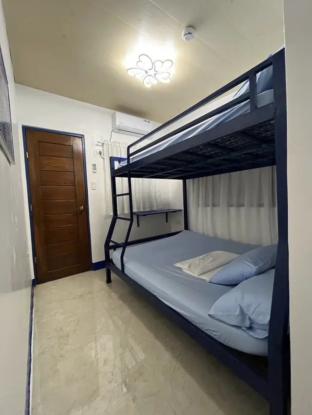 Room with a bunk bed, wooden door and air conditioner