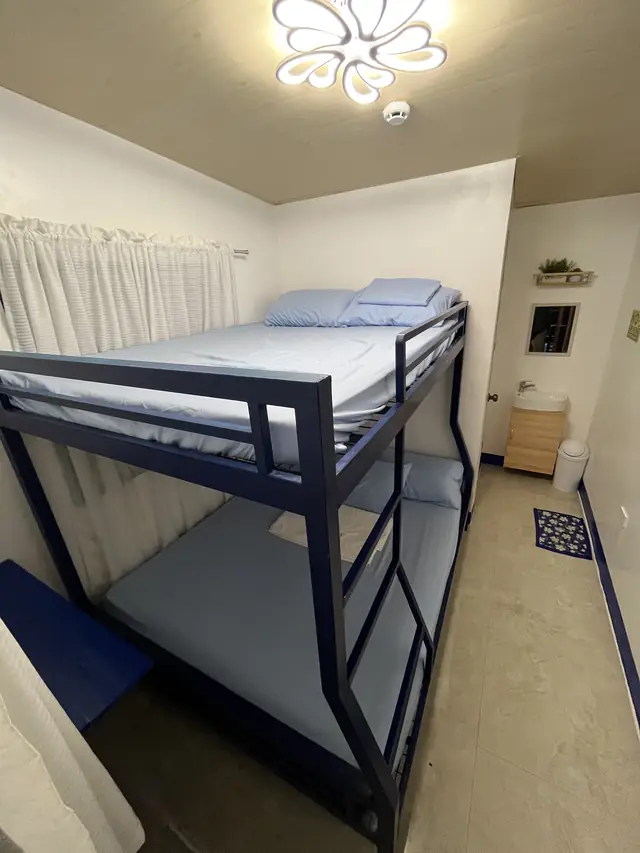 Room with a full-size bunk bed and blue sheets