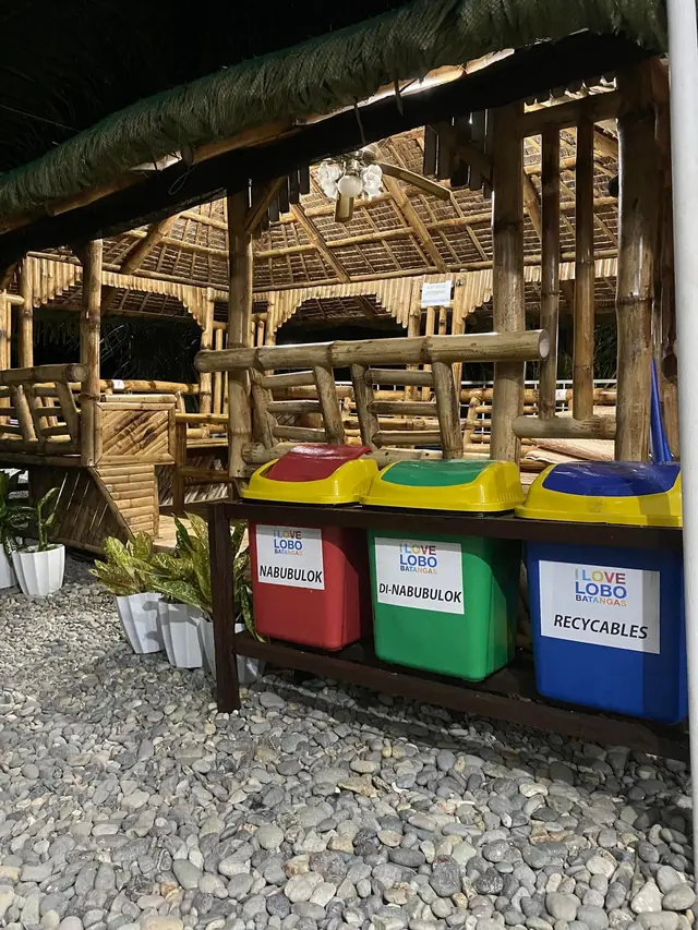 Nipa hut with sorting bins on the pebble shore